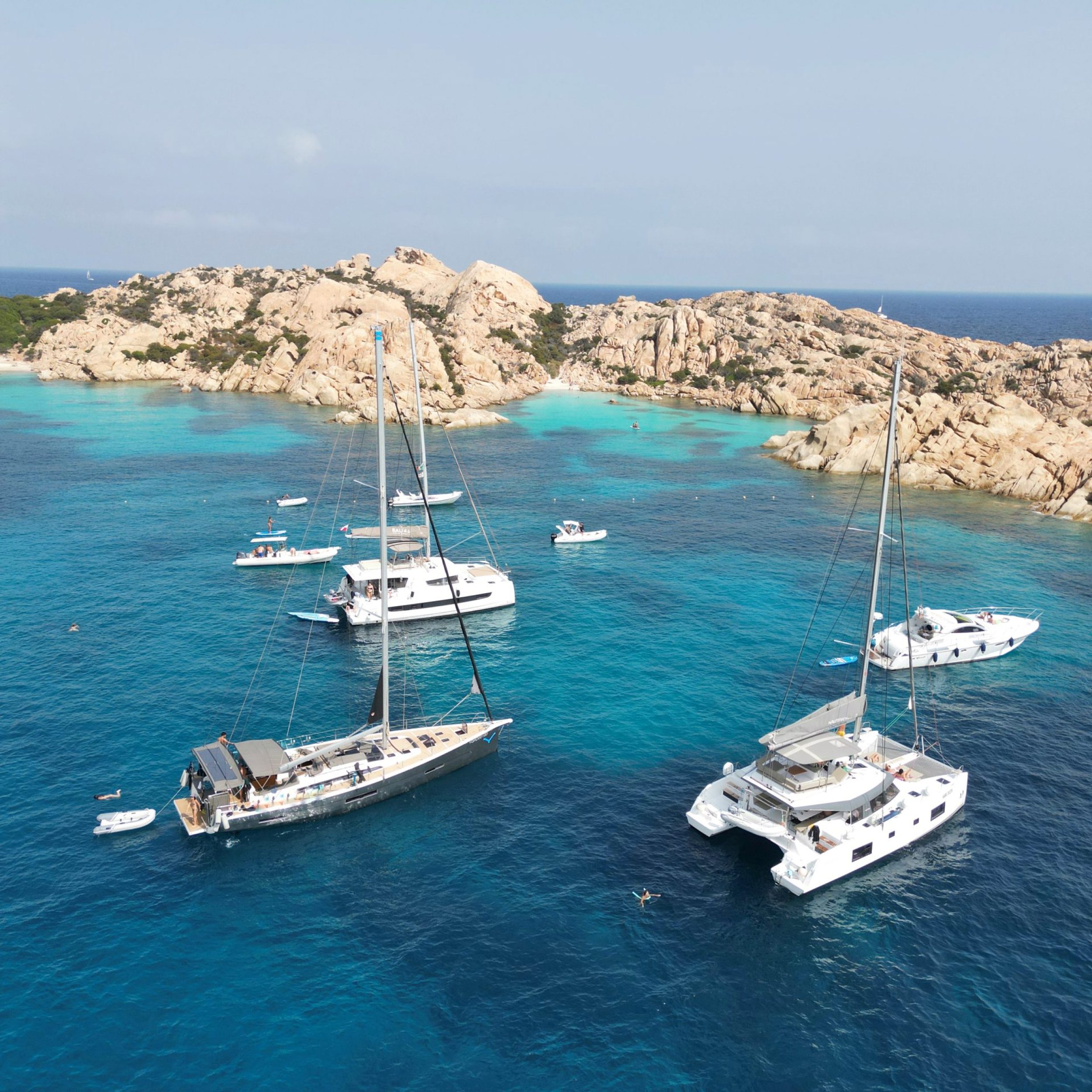 Luxury catamaran sailing in Sardinia: Aerial view of a boat on crystal-clear waters, perfect for a 7-night all-inclusive sailing adventure.